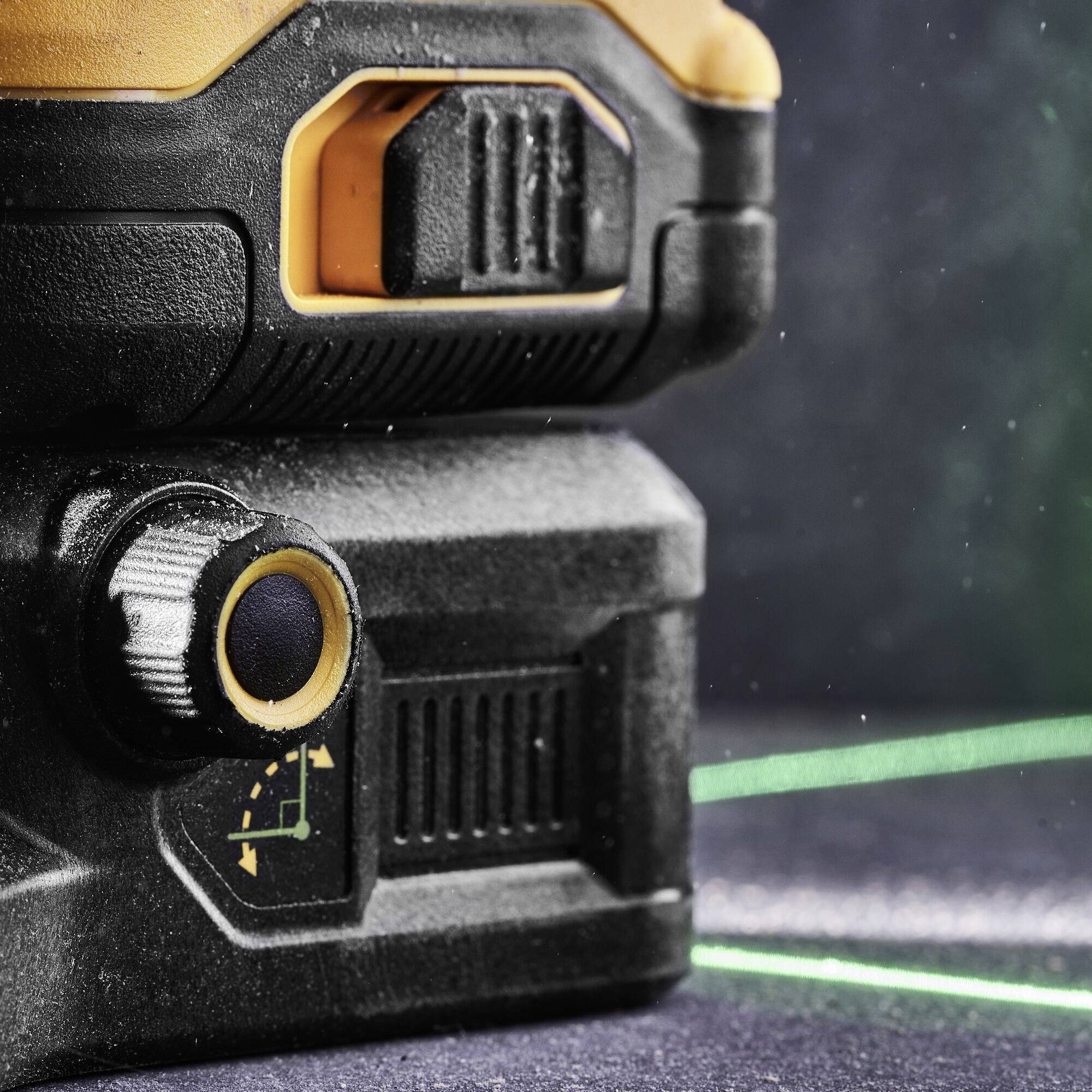 Gros plan d'un laser noir et orange avec fonction de niveau à bulle ; un rayon laser vert est visible, augmentant la précision.
