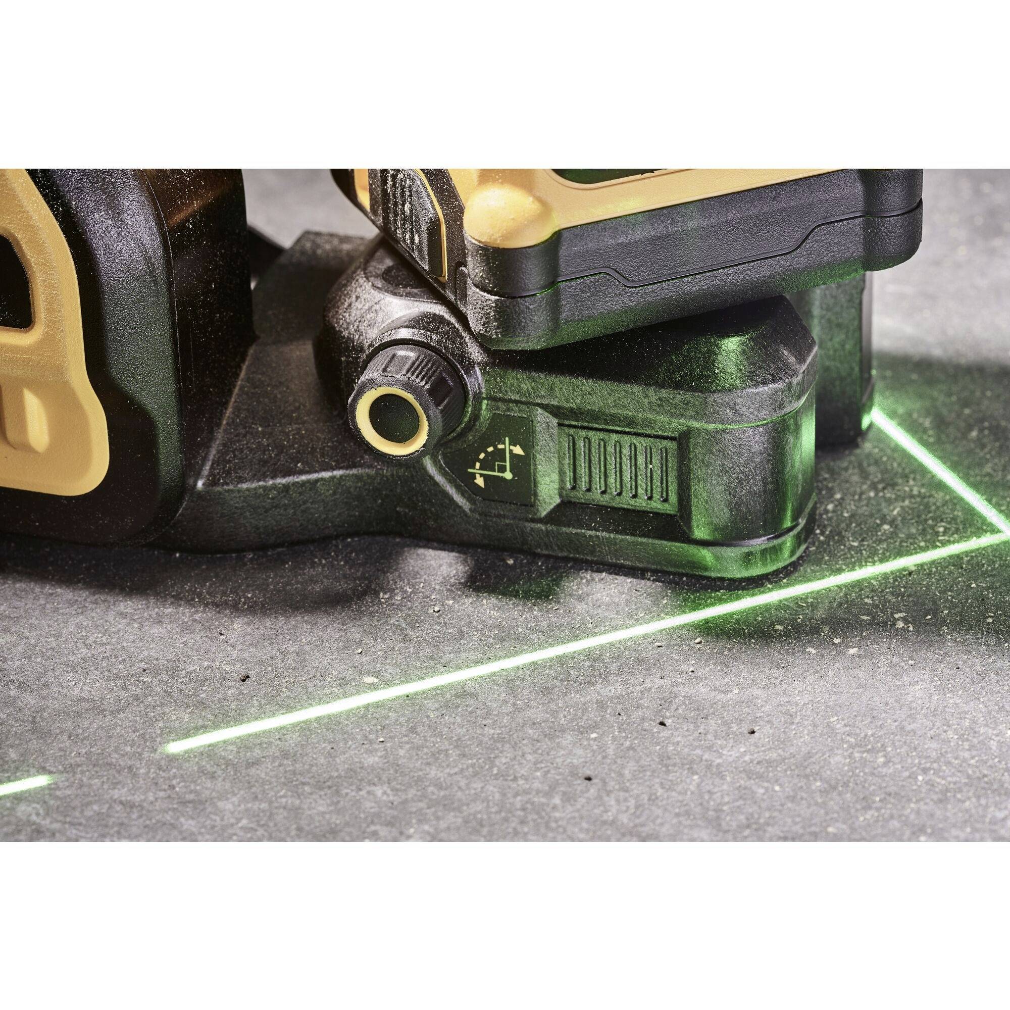 Un laser à lignes croisées projetant une ligne horizontale et une ligne verticale vertes sur une surface grise pour faciliter des mesures précises.