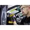 Une personne répare une voiture avec un tournevis électrique. Elle porte des lunettes de protection et des gants. La voiture est ouverte.