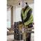 Un ouvrier portant un casque de chantier et un gilet de sécurité coupe du métal avec un disque à tronçonner sur un chantier. Des étincelles jaillissent pendant la coupe.
