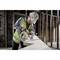 Une personne portant un casque de protection et un gilet de sécurité travaille avec une scie circulaire électrique sur un chantier de construction.