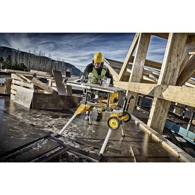 Ouvrier portant un casque jaune et un gilet de protection, utilisant une scie circulaire sur un chantier de construction. Structure en bois en arrière-plan, ciel dégagé.