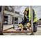 Travailleur portant un casque et des vêtements de protection meulant du métal avec une meuleuse d'angle sur un chantier. Environnement avec échafaudage et construction en cours.