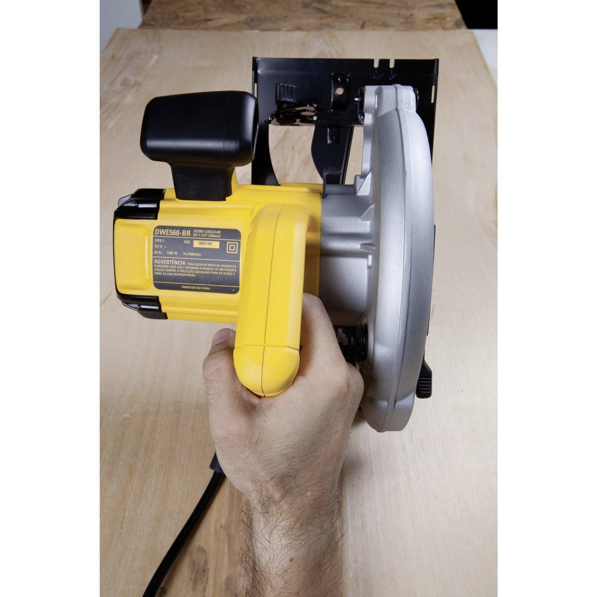 Un outil électrique jaune et performant avec une poignée noire est tenu par une main, prêt pour le travail du bois.