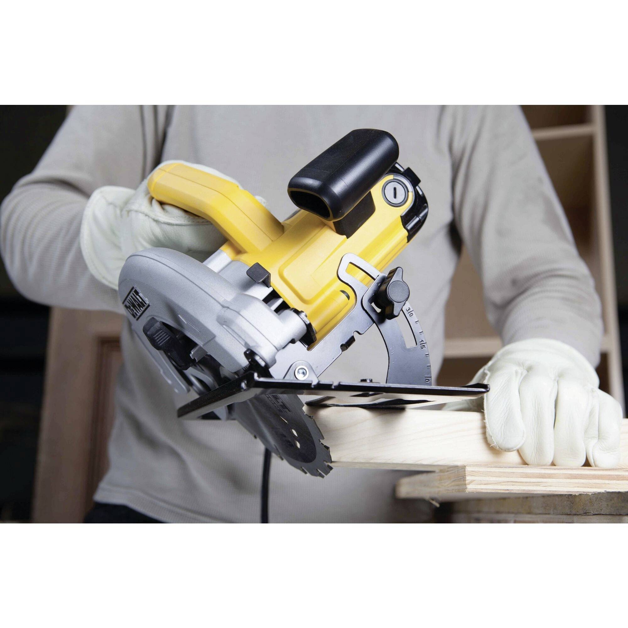 Une personne scie une planche en bois avec une scie circulaire jaune portative. Elle porte des gants de protection.
