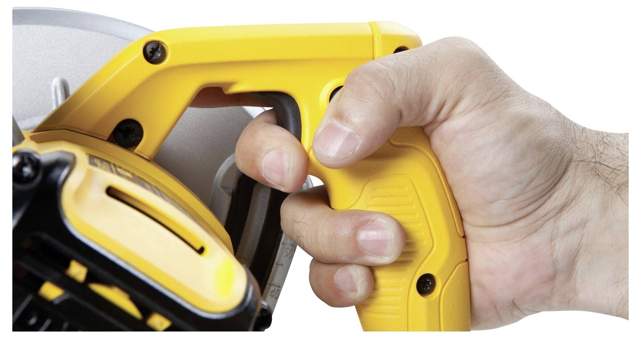 Une main tient la poignée d'une scie électrique jaune, prête à être utilisée. L'accent est mis sur la détente du déclencheur.