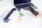 Un scanner sur une table numérise un document ; à côté se trouvent un smartphone et d'autres papiers. Un ordinateur portable est visible en arrière-plan.