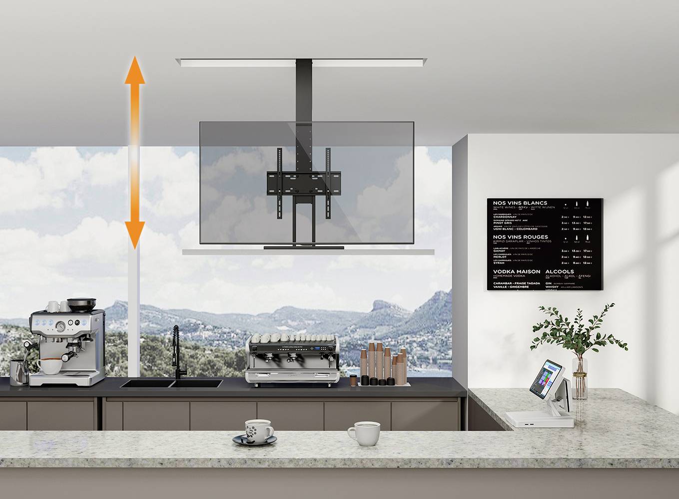 Une cuisine moderne avec une fenêtre panoramique offrant une vue sur un paysage montagneux. Sur le plan de travail, des machines à café et une tablette sont disposées.