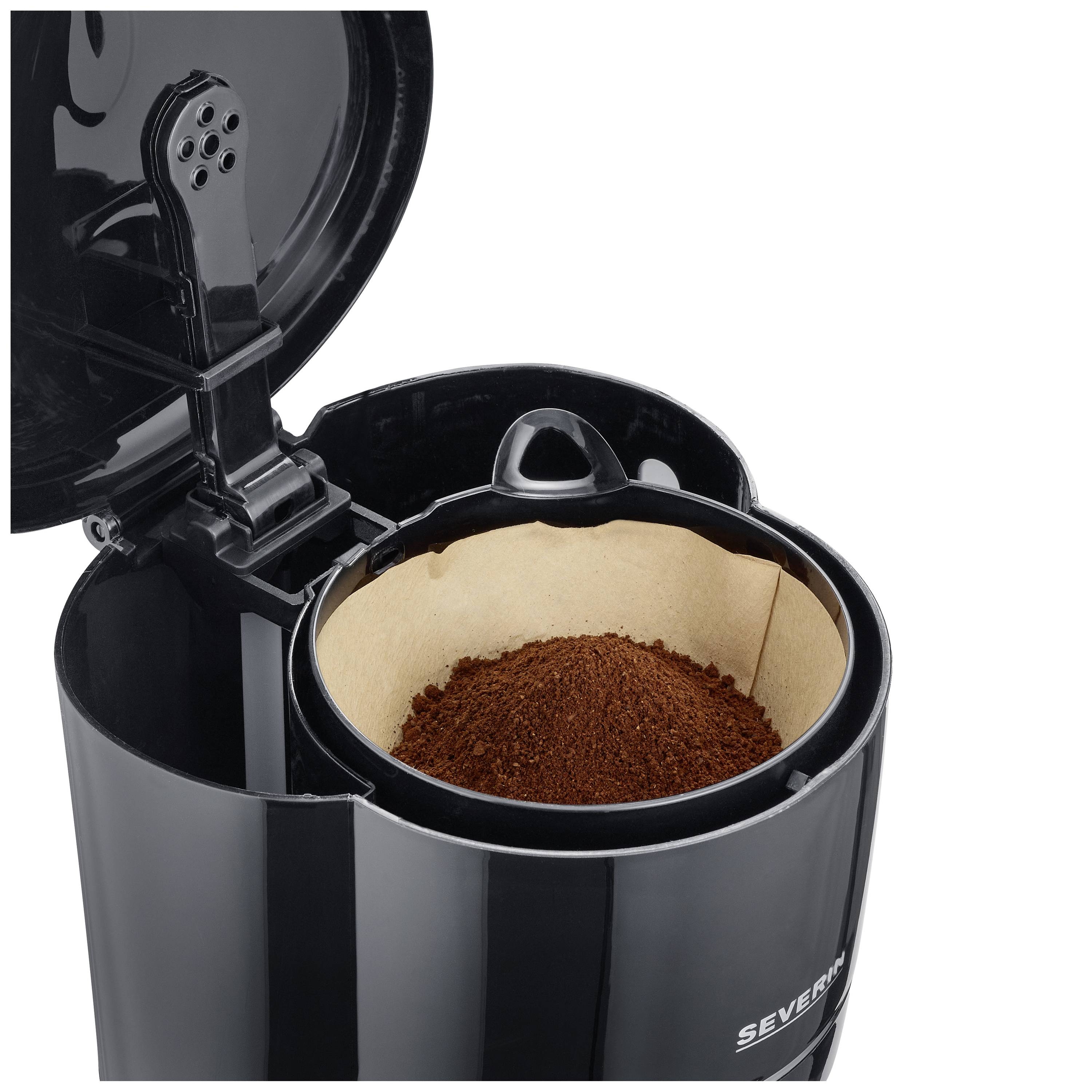 Machine à café noire avec le couvercle ouvert, montrant le filtre avec du café moulu.