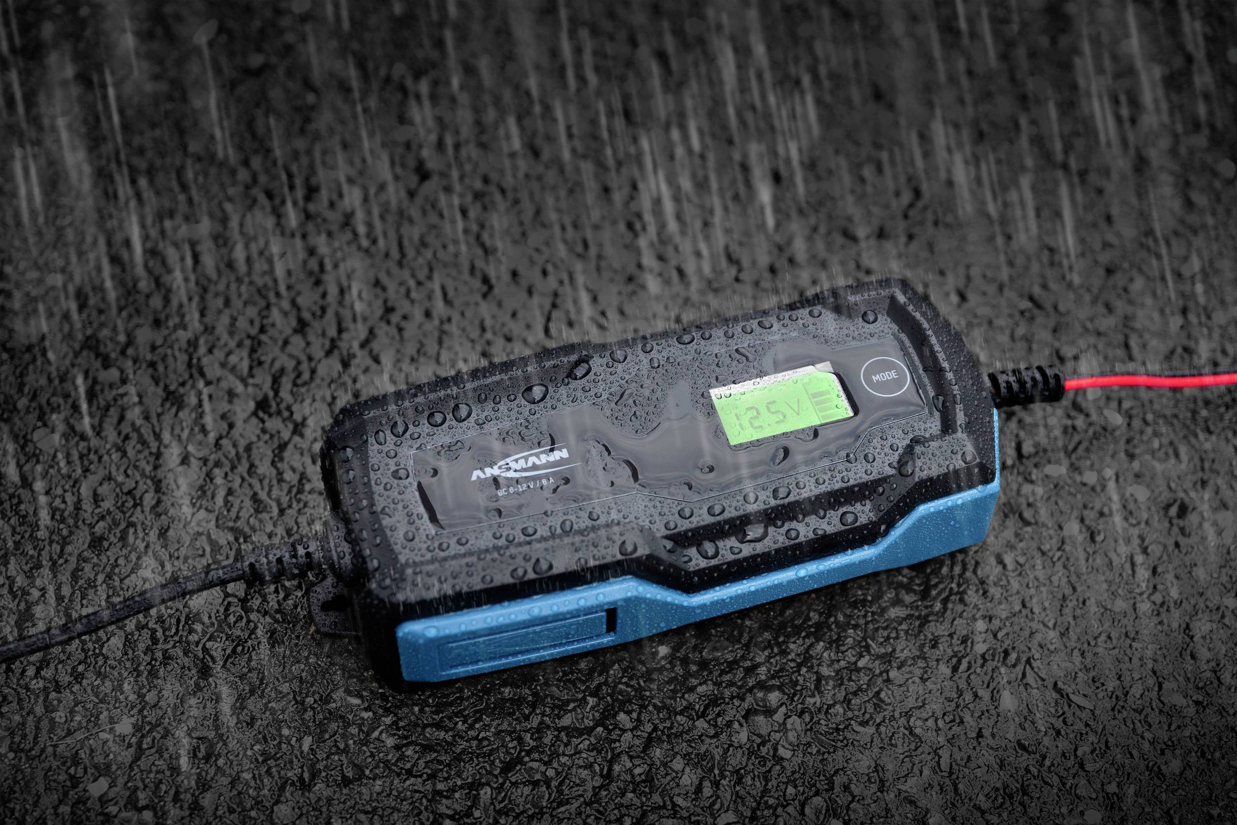 Chargeur couvert de gouttes de pluie, posé sur une surface humide. Démontre sa résistance aux intempéries et son utilisation en extérieur.
