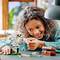 Un enfant sourit en jouant avec un ensemble Lego sur une table. L'ensemble représente une scène avec une figurine et un panneau portant l'inscription « Privet Drive ».
