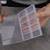 Une personne ouvre un organiseur en plastique transparent à plusieurs compartiments sur une table.