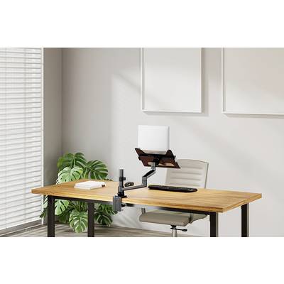 Un espace de travail moderne avec une table en bois, une chaise ergonomique et un support de moniteur. La lumière tombe à travers les stores sur une plante.