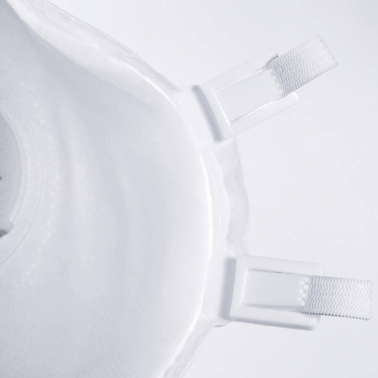 Masque de protection blanc avec des bandes élastiques, partiellement visible sur l'image, sur un fond clair.