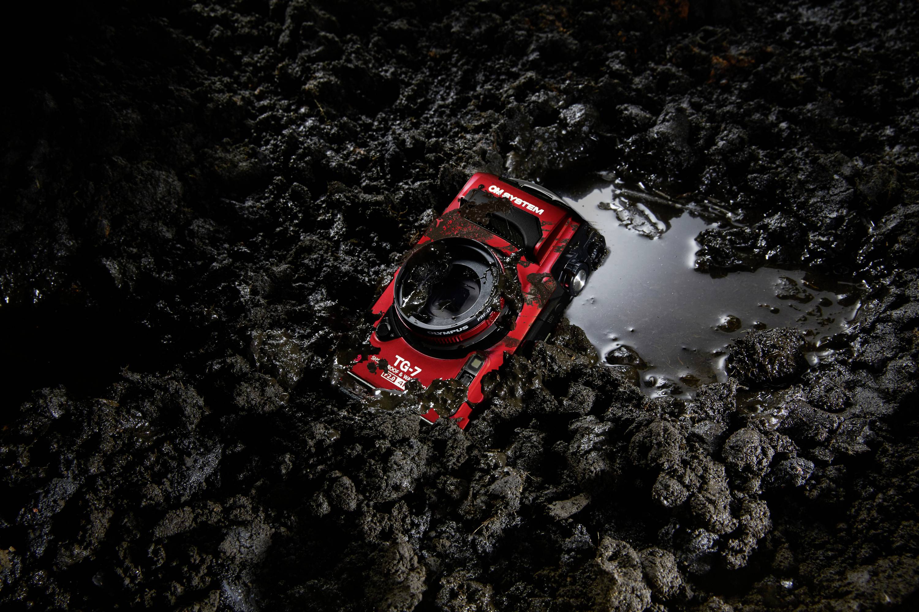Une carte graphique rouge et noire est posée sur un fond sombre et boueux, partiellement entourée d'eau.