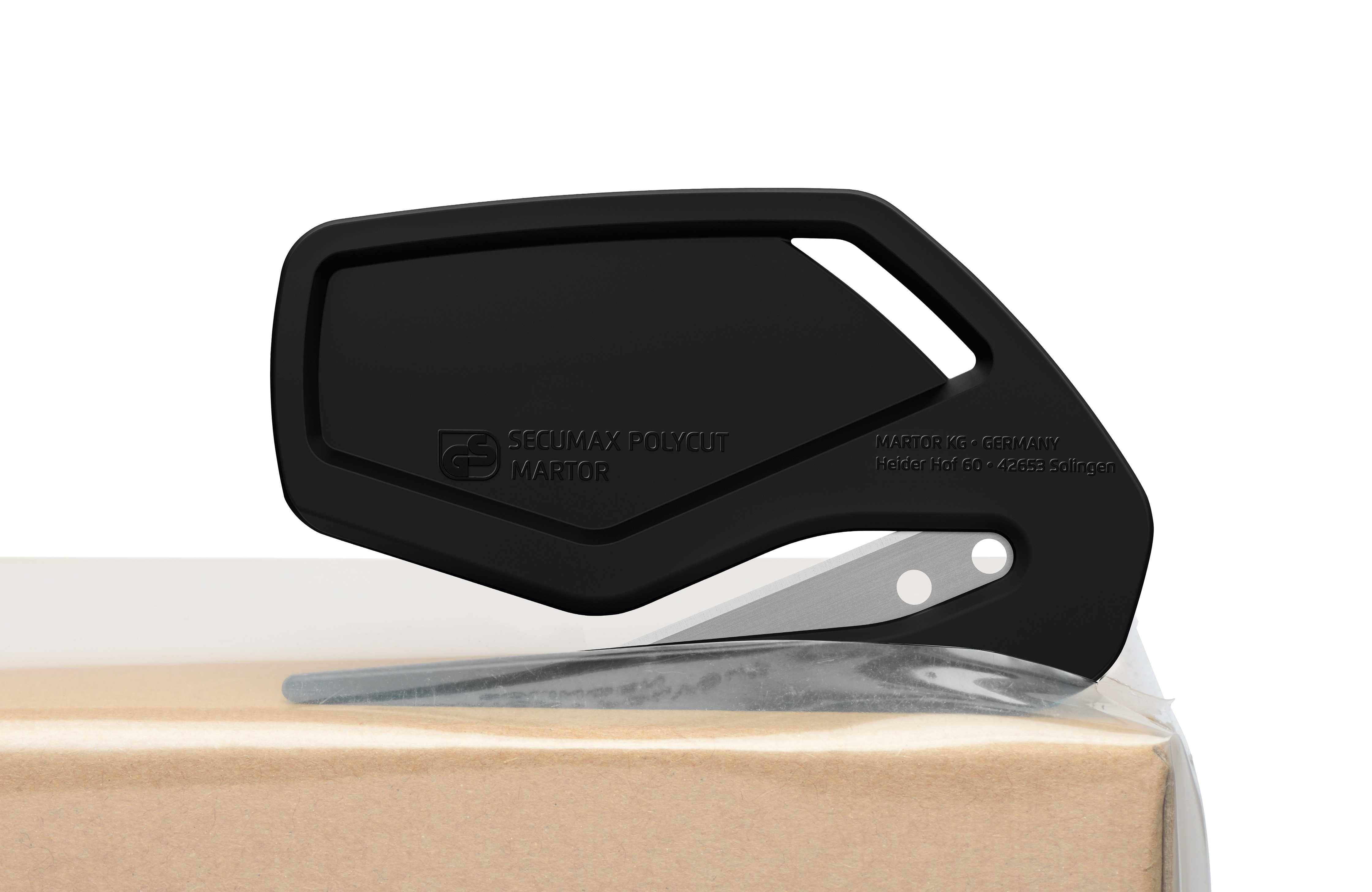 Un ouvre-carton noir coupe dans un carton brun. Il est fabriqué en plastique avec une lame métallique tranchante.