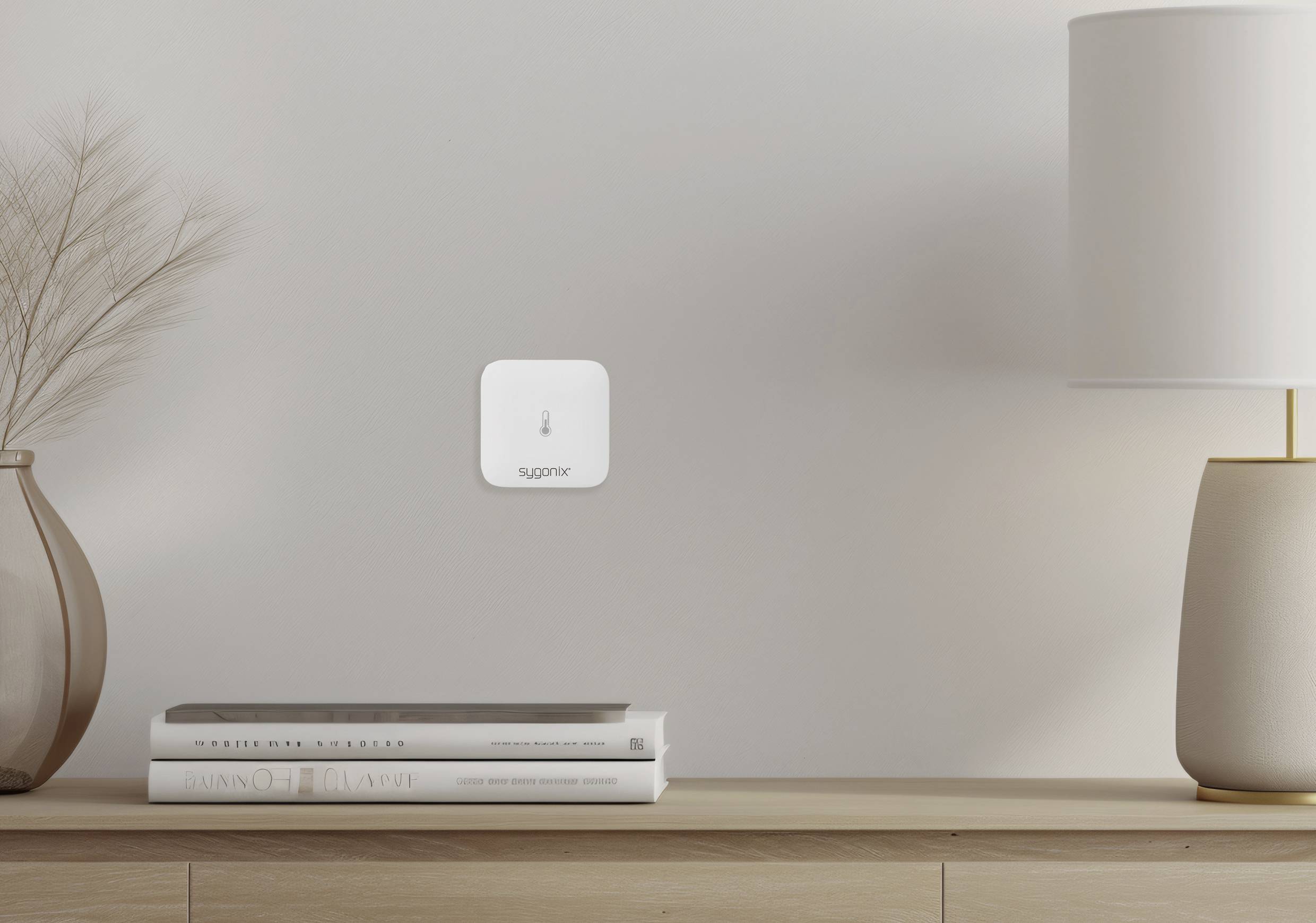 Un bureau minimaliste avec un vase, des livres et une lampe. Un petit capteur blanc sur le mur affiche le mot « supreme ».