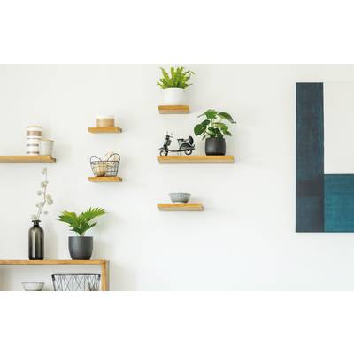Mur blanc minimaliste avec des étagères flottantes en bois contenant des plantes en pot, des paniers et des éléments de décoration, plus un grand tableau abstrait bleu sur la droite.