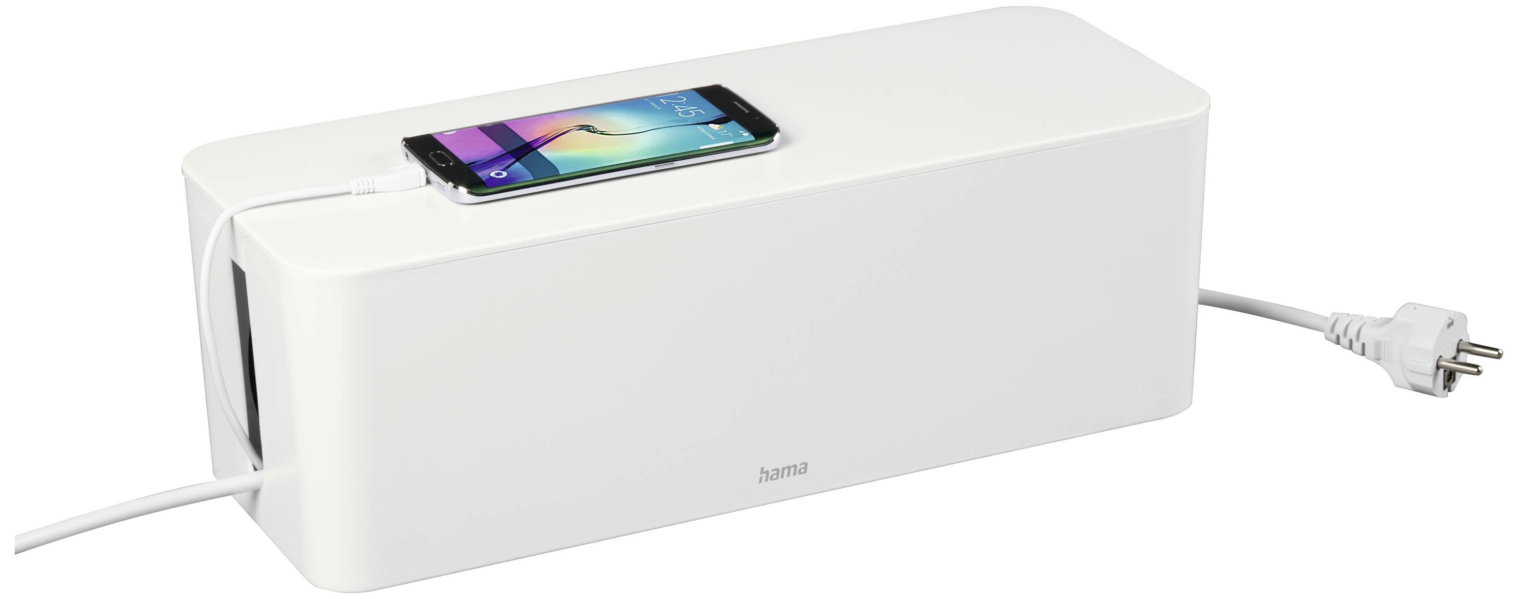 Une boîte blanche de rangement pour câbles avec un smartphone posé dessus en cours de chargement. Un câble relie la boîte à une prise électrique.