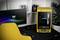 Un boîtier d'ordinateur jaune avec un panneau latéral transparent, posé sur un bureau avec une chaise pivotante jaune, un écran, un clavier et des écouteurs.