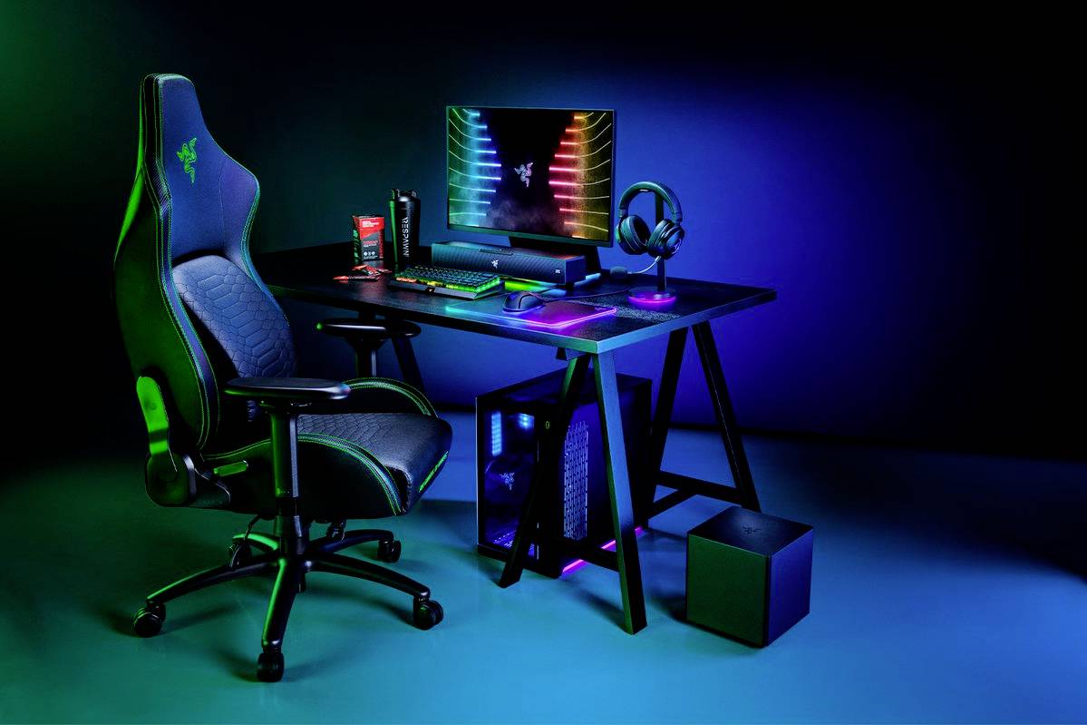 Configuration de jeu avec bureau éclairé, chaise gaming, moniteur à l'écran coloré, clavier, souris et casque audio.