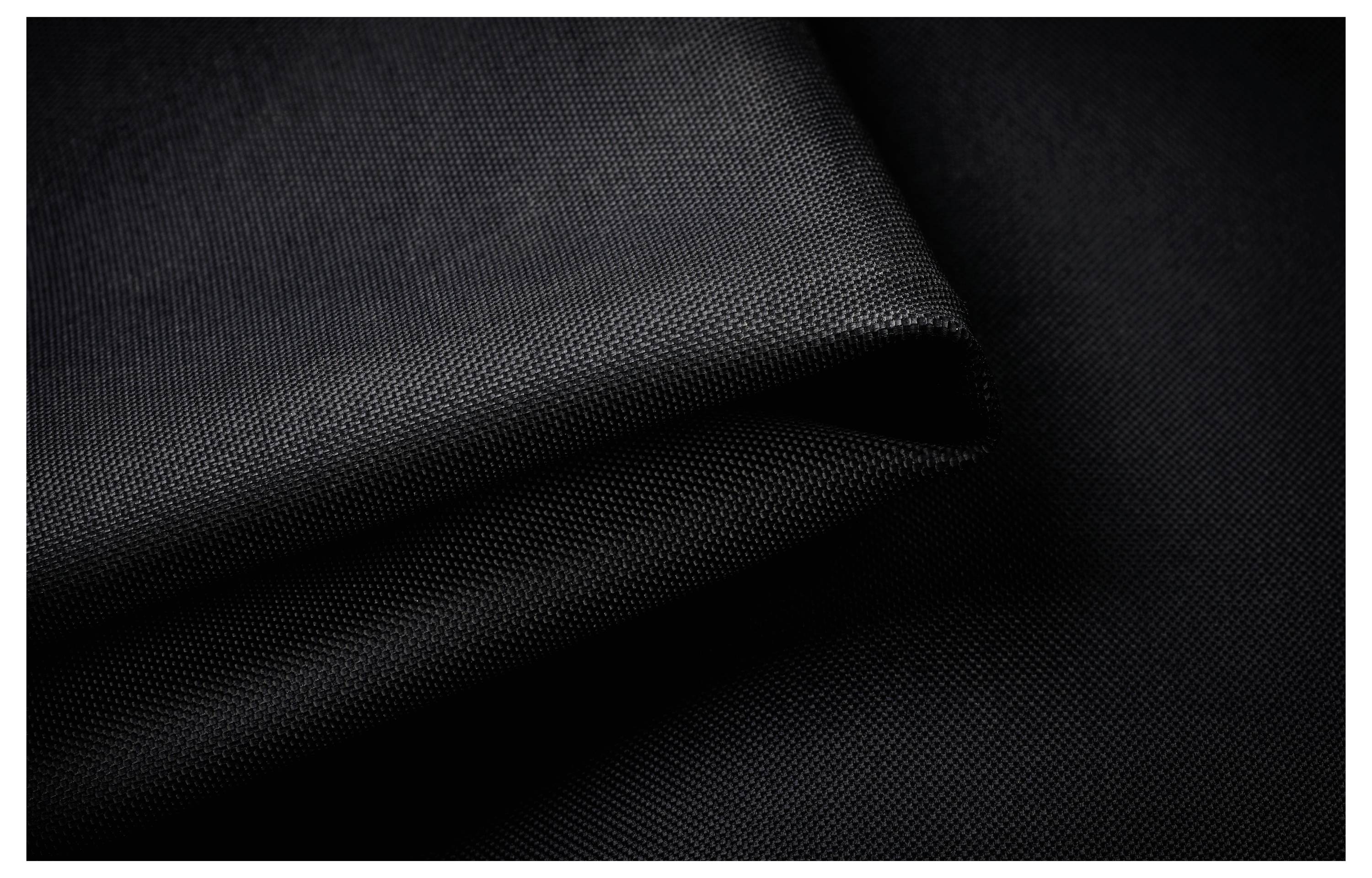 Une photo en gros plan d'un tissu noir plié, lisse et à la surface texturée, mettant en valeur les détails du tissage et dégageant un sentiment d'élégance et de simplicité.