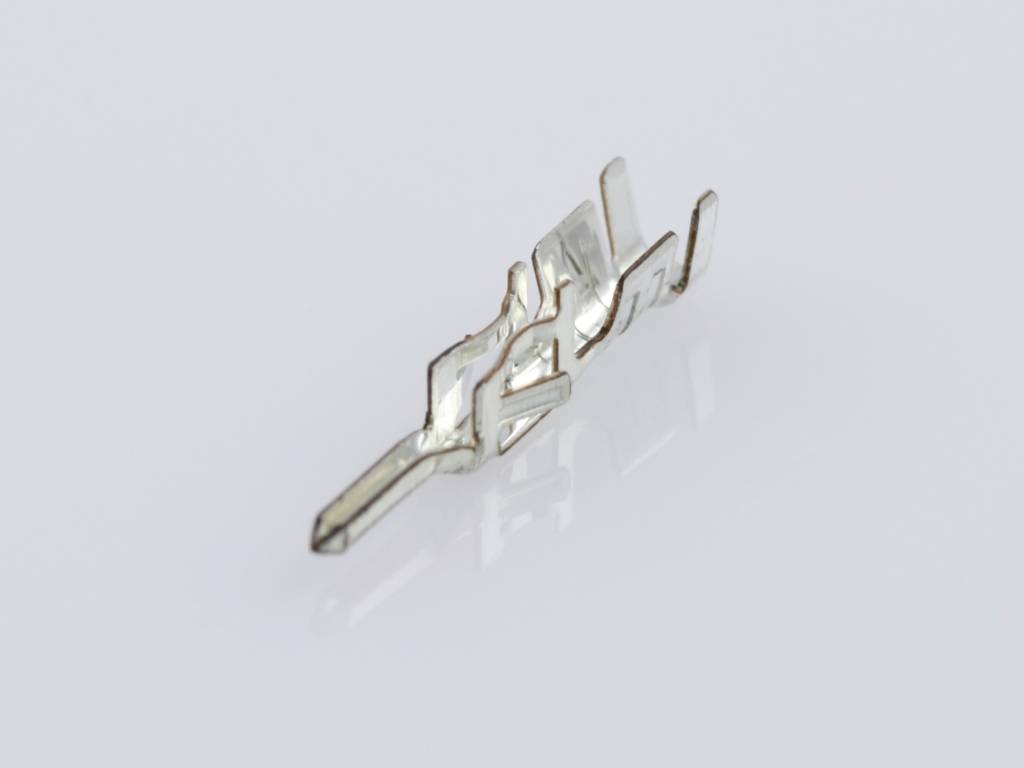 Une broche de contact métallique unique sur une surface blanche. Elle présente une forme complexe et dentelée et sert aux connexions électroniques.