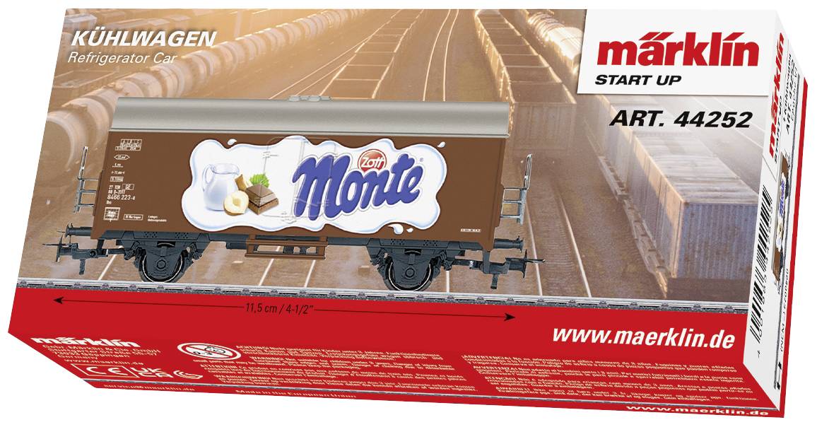 Modèle de wagon réfrigéré à l'échelle 1:87 avec publicité 'Monte' sur carton rouge Märklin. L'arrière-plan montre un réseau ferroviaire.