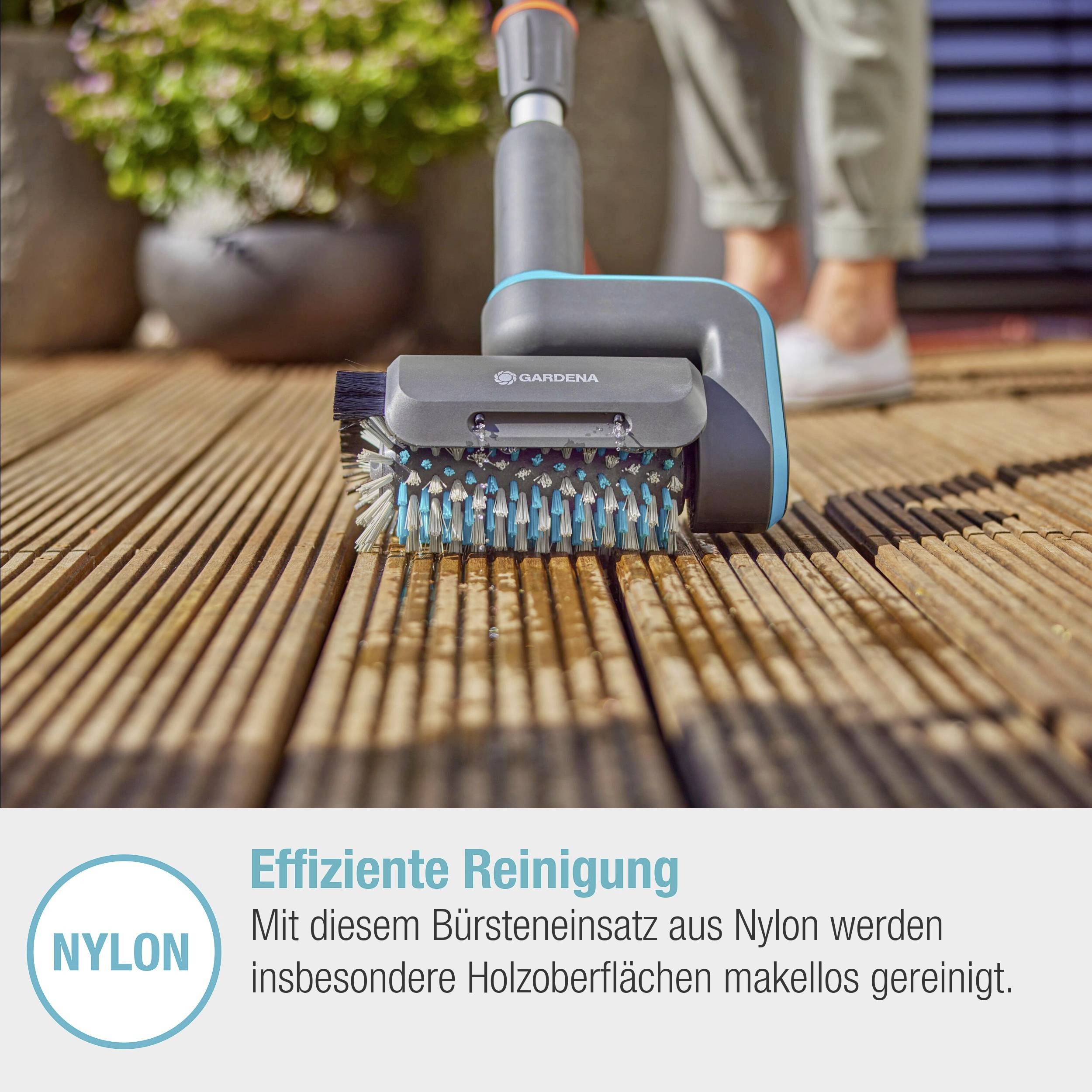 'Une personne nettoie un plancher en bois avec une brosse en nylon de Gardena. Gros plan sur la brosse passant sur les lames de bois. Nettoyage efficace.'