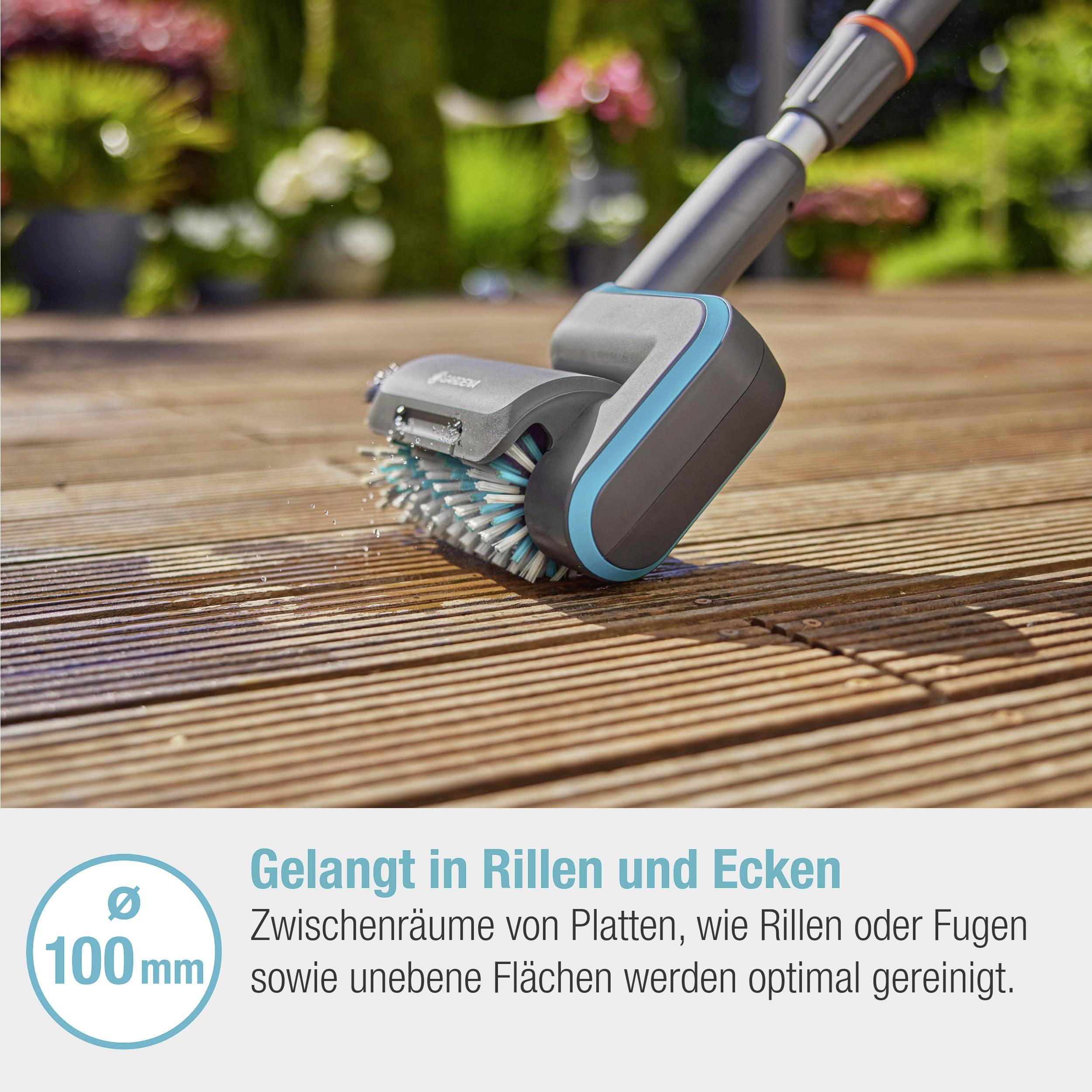 "S'infiltre dans les rainures et les coins" : Gros plan d'une brosse de nettoyage sur une terrasse en bois, soulignant le nettoyage des joints. Diamètre de brosse de 100 mm.