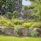 Un arroseur moderne irrigue un jardin verdoyant avec des fleurs et des buissons. Les gouttelettes d'eau dans l'air créent une ambiance rafraîchissante.