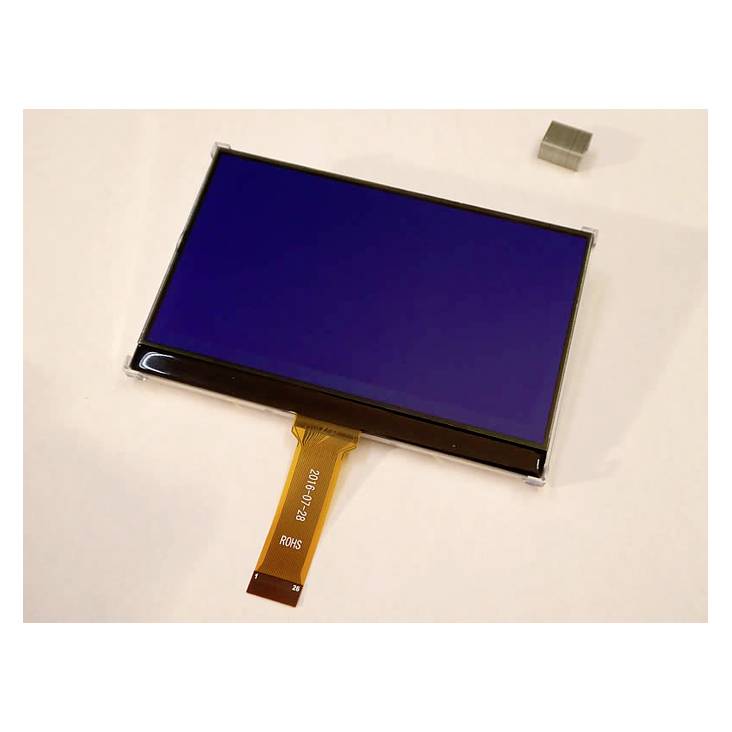 Un petit écran LCD rectangulaire avec un câble de connexion flexible est posé sur un fond clair. À côté de l'écran se trouve un petit cube magnétique.