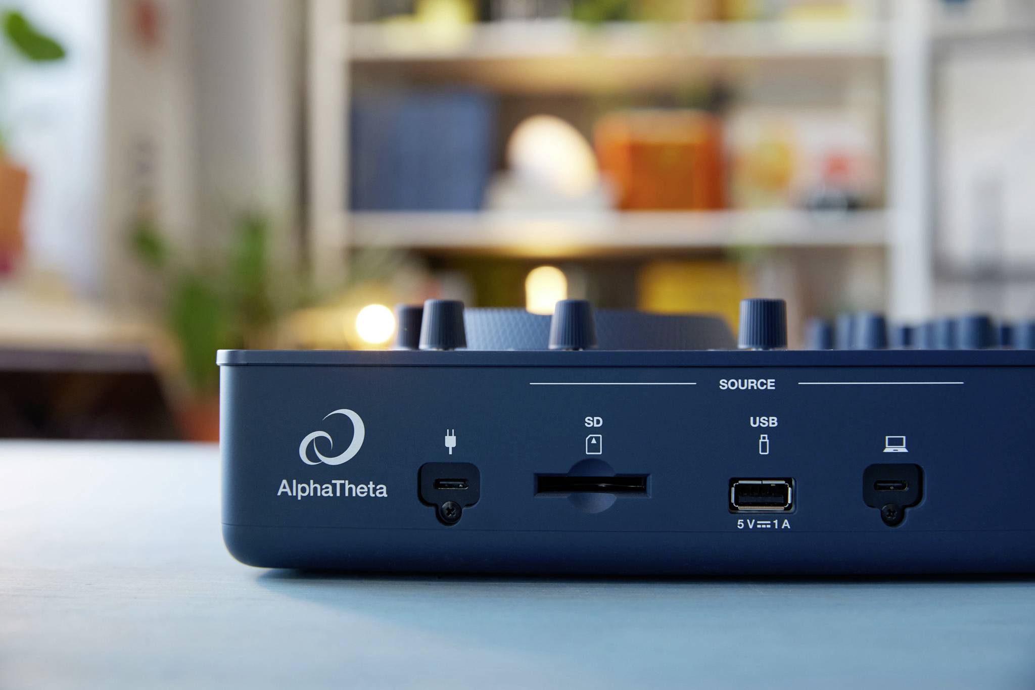 Face avant d'un appareil électronique avec des ports pour carte SD, USB et alimentation électrique. Le nom de marque 'AlphaTheta' est visible.