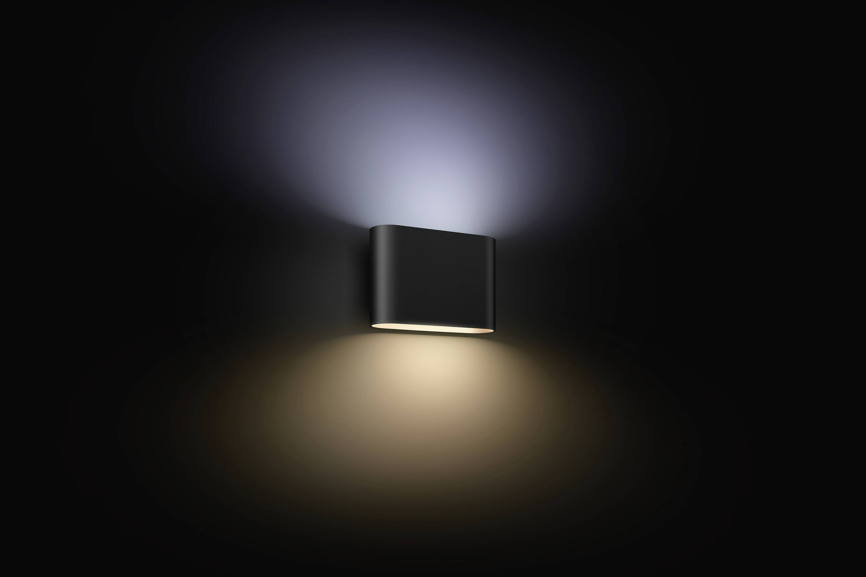 Applique murale éclairant vers le haut et vers le bas, créant une lumière douce et diffuse sur un mur sombre. Design minimaliste.