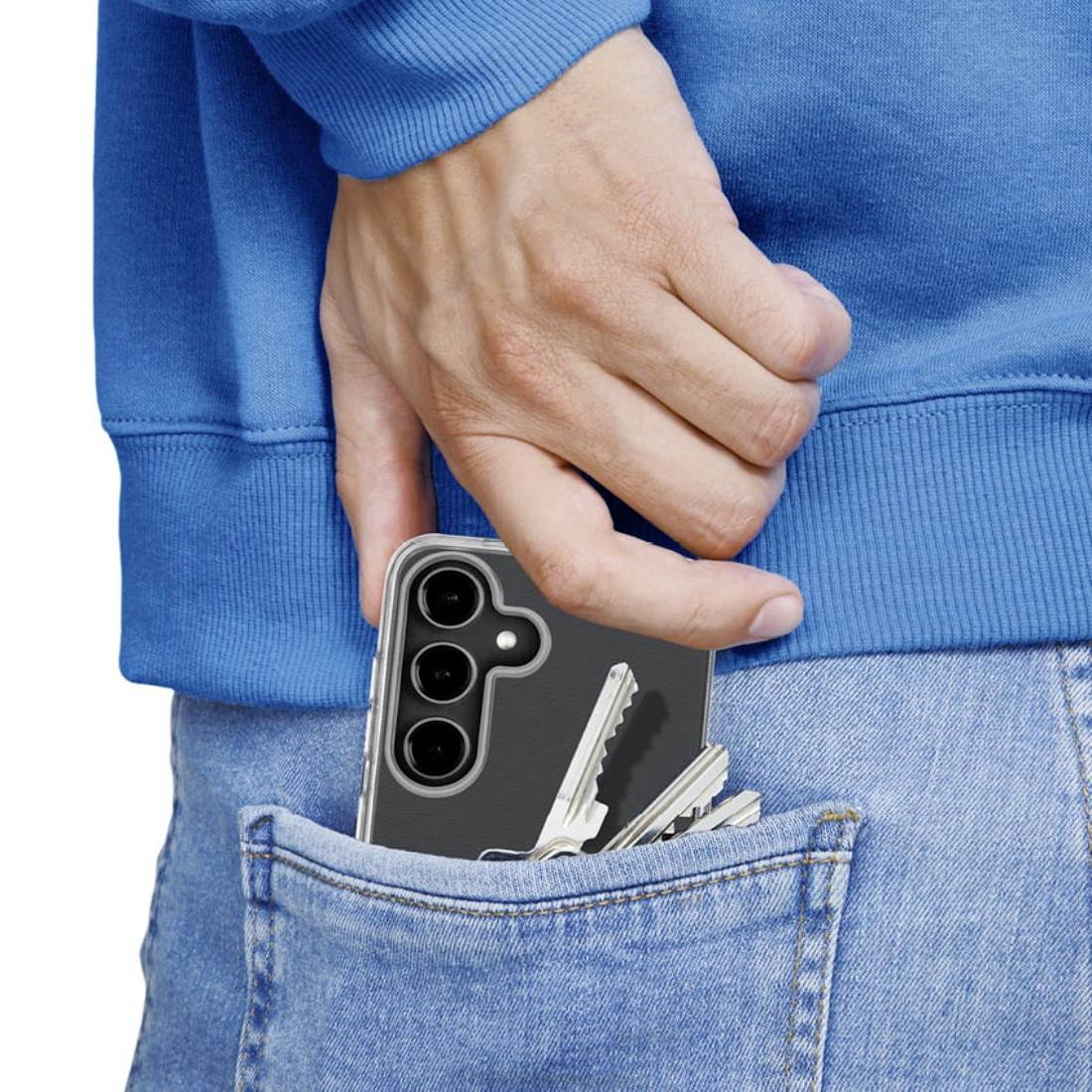 Une main glisse un smartphone avec des clés dans la poche arrière d'un jean bleu.