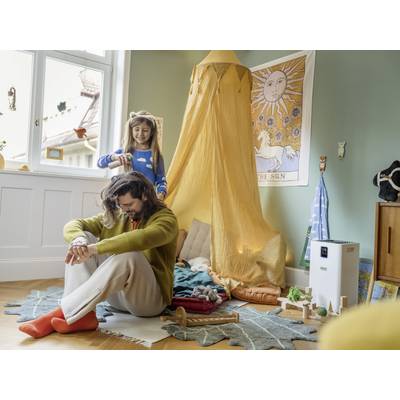 Une jeune fille coiffe les cheveux d'un homme dans une chambre d'enfant douillette avec un baldaquin et des jouets.