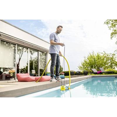Un homme se tient au bord de la piscine et utilise une pompe jaune pour nettoyer l'eau. Des sièges et des arbres sont visibles en arrière-plan.