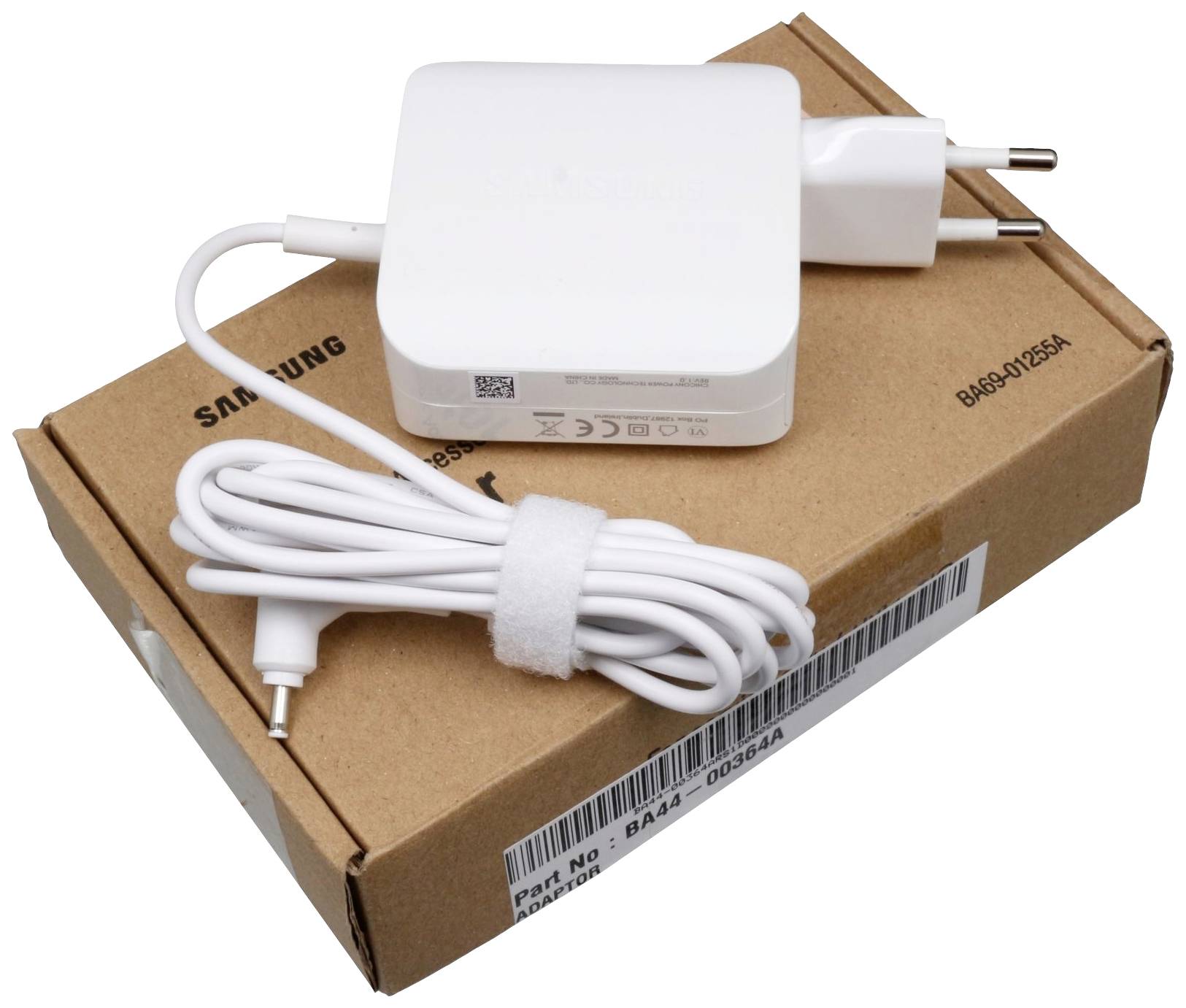 Un chargeur de portable blanc avec une prise européenne et un câble, placé sur un carton brun portant le logo Samsung.