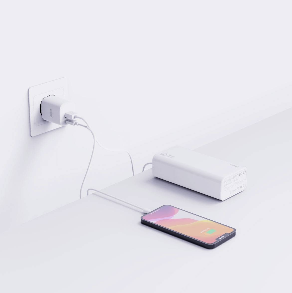 Un smartphone est en train d'être chargé à l'aide d'un câble de charge connecté à une batterie externe qui est elle-même branchée à une prise électrique. L'écran du téléphone affiche l'écran de charge.