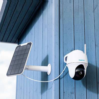 Caméra de surveillance installée sur un mur bleu, alimentée par un panneau solaire.