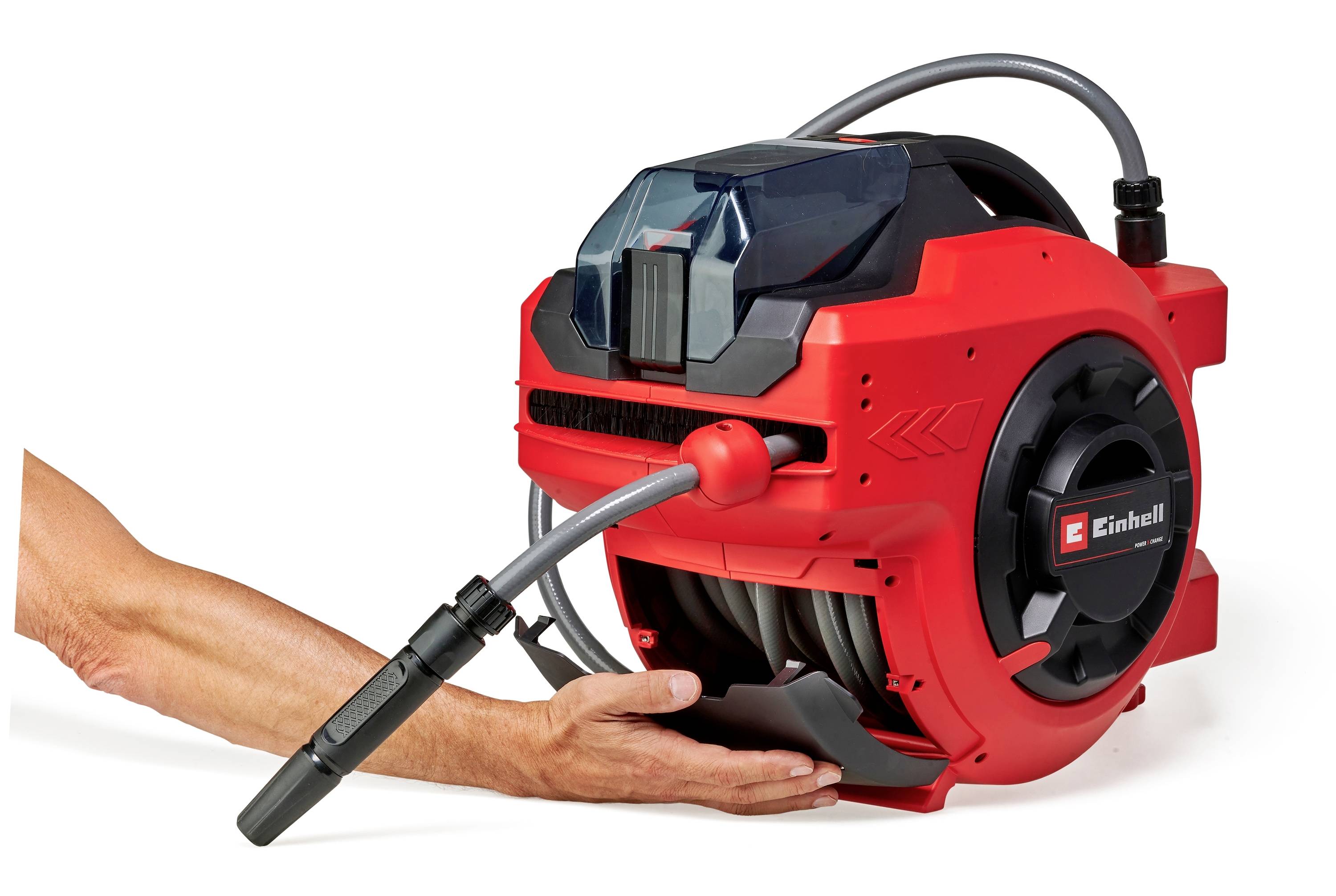 Une personne tient un enrouleur automatique de tuyau rouge. Le tuyau est enroulé correctement, un logo Einhell est visible.