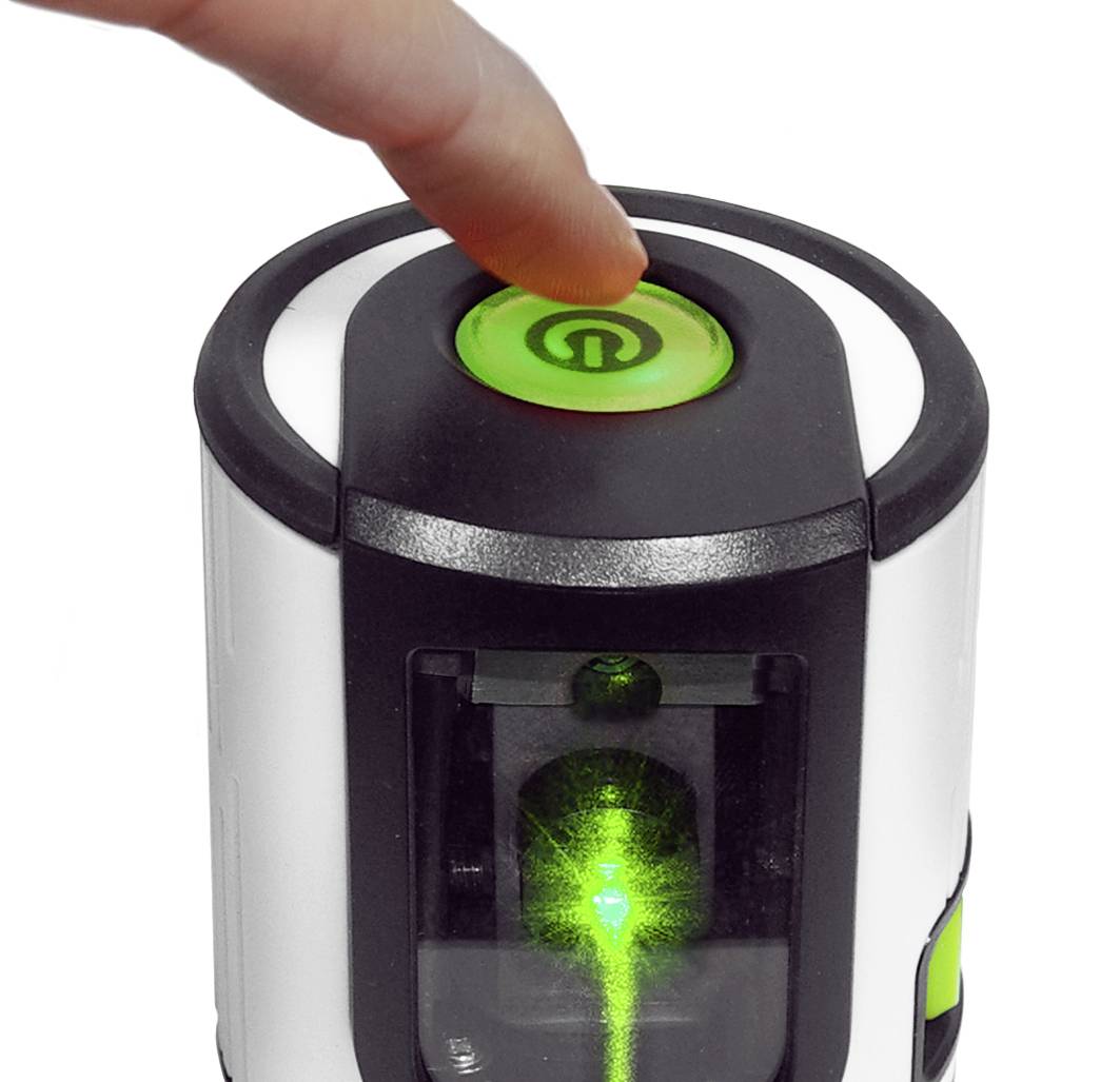 Un doigt touche une touche de mise en marche sur un appareil scientifique avec un voyant vert et un affichage laser.