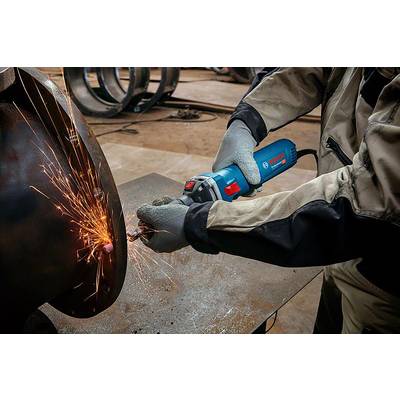 Un ouvrier utilise une meuleuse d'angle pour travailler le métal. Des étincelles jaillissent au point de contact. Des vêtements de protection et des gants sont portés.