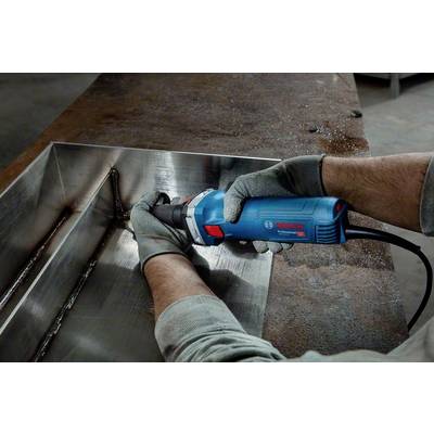 Une personne utilise un outil électrique bleu pour poncer des soudures sur une pièce métallique. Elle porte des gants de protection gris.
