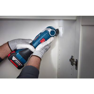 Une personne porte des gants et utilise un outil électrique pour découper un trou dans une paroi d'armoire.