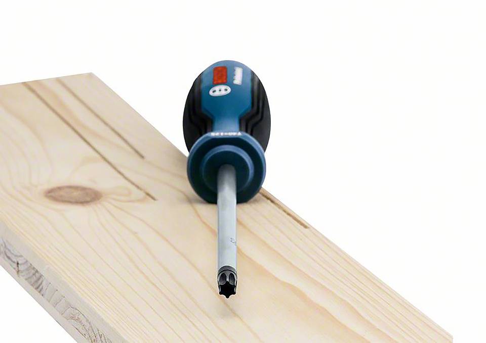 Un tournevis à poignée bleue est posé en diagonale sur une planche de bois claire. Le tournevis a un embout cruciforme.