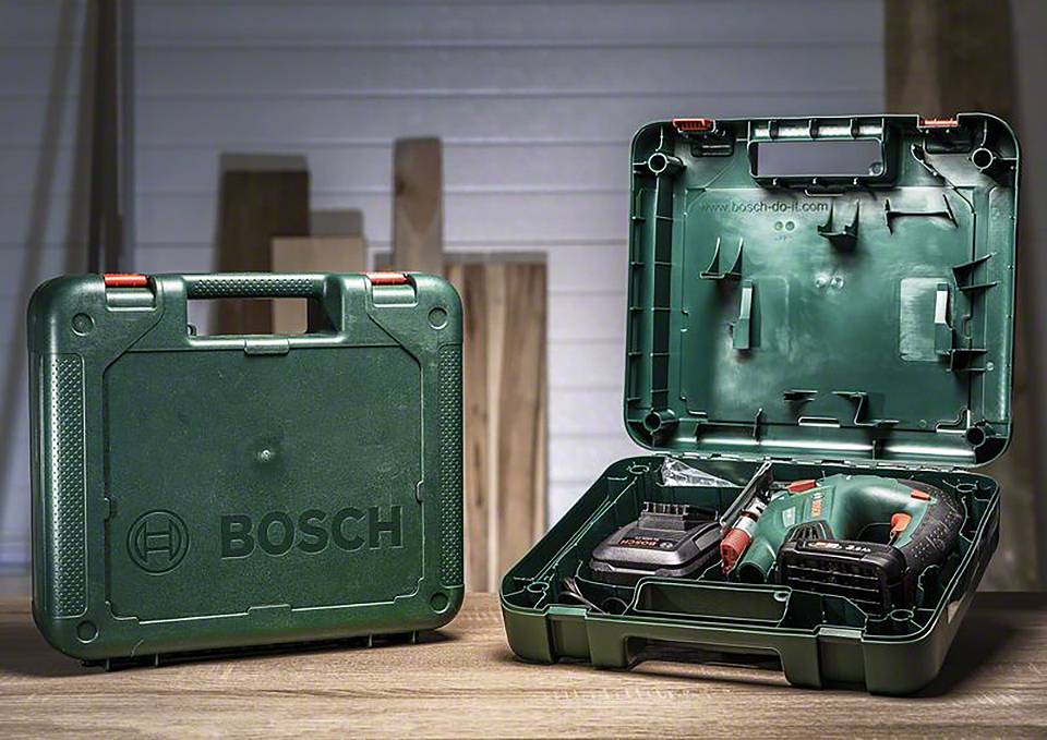 Une mallette Bosch verte ouverte contenant deux perceuses est posée sur une table. Une mallette fermée se trouve à côté.