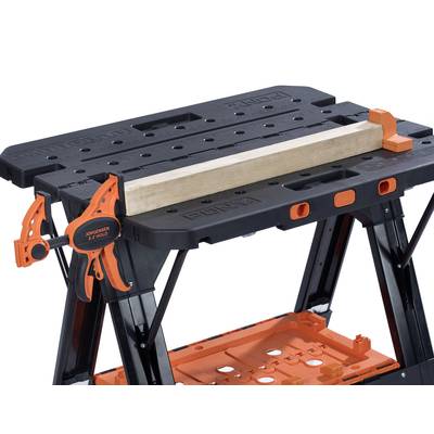 Établi avec surface noire, support d'outils orange et pièce de bois. Idéal pour les bricoleurs et les projets de construction.