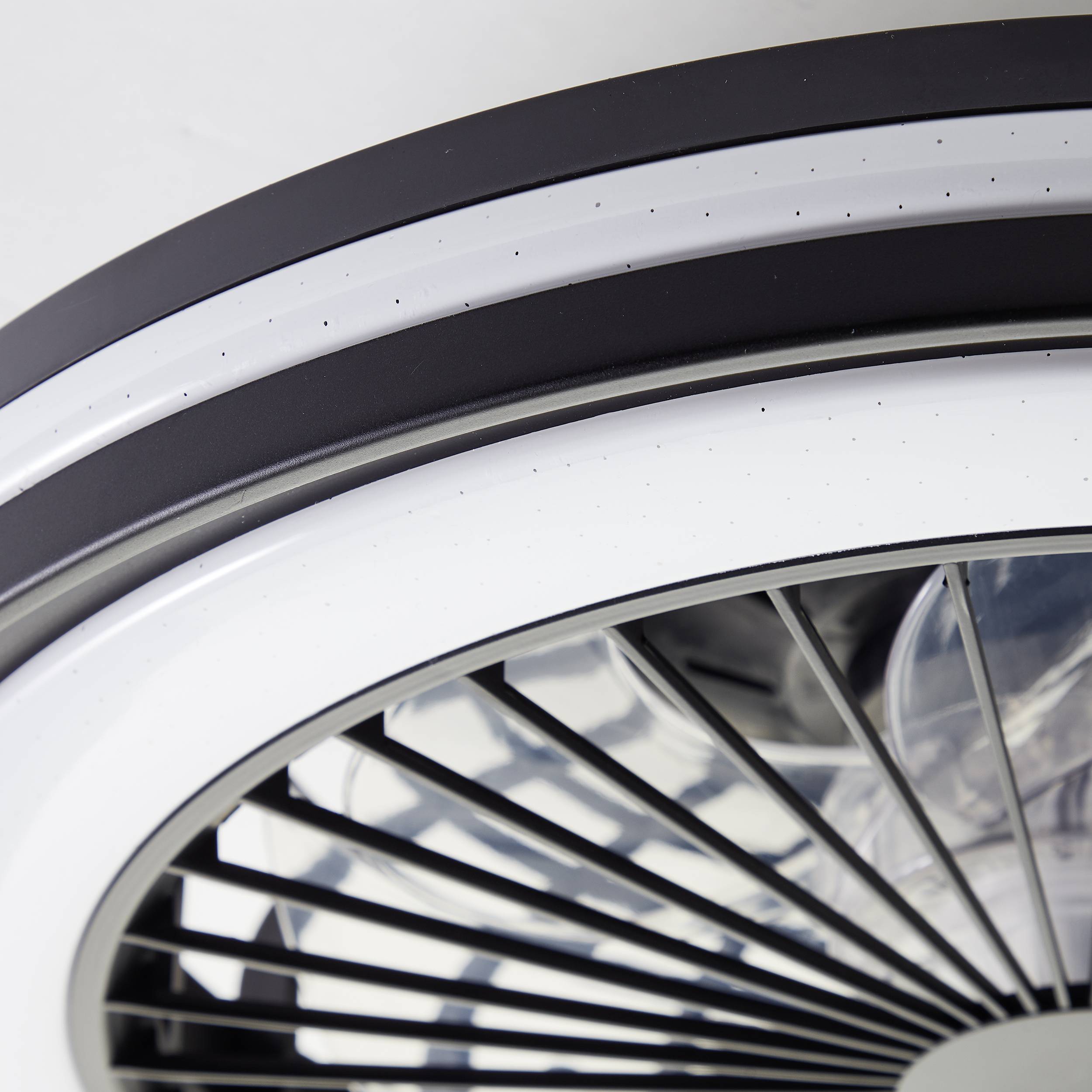 Un gros plan d'un ventilateur moderne avec des pales noires et blanches disposées selon un motif géométrique.