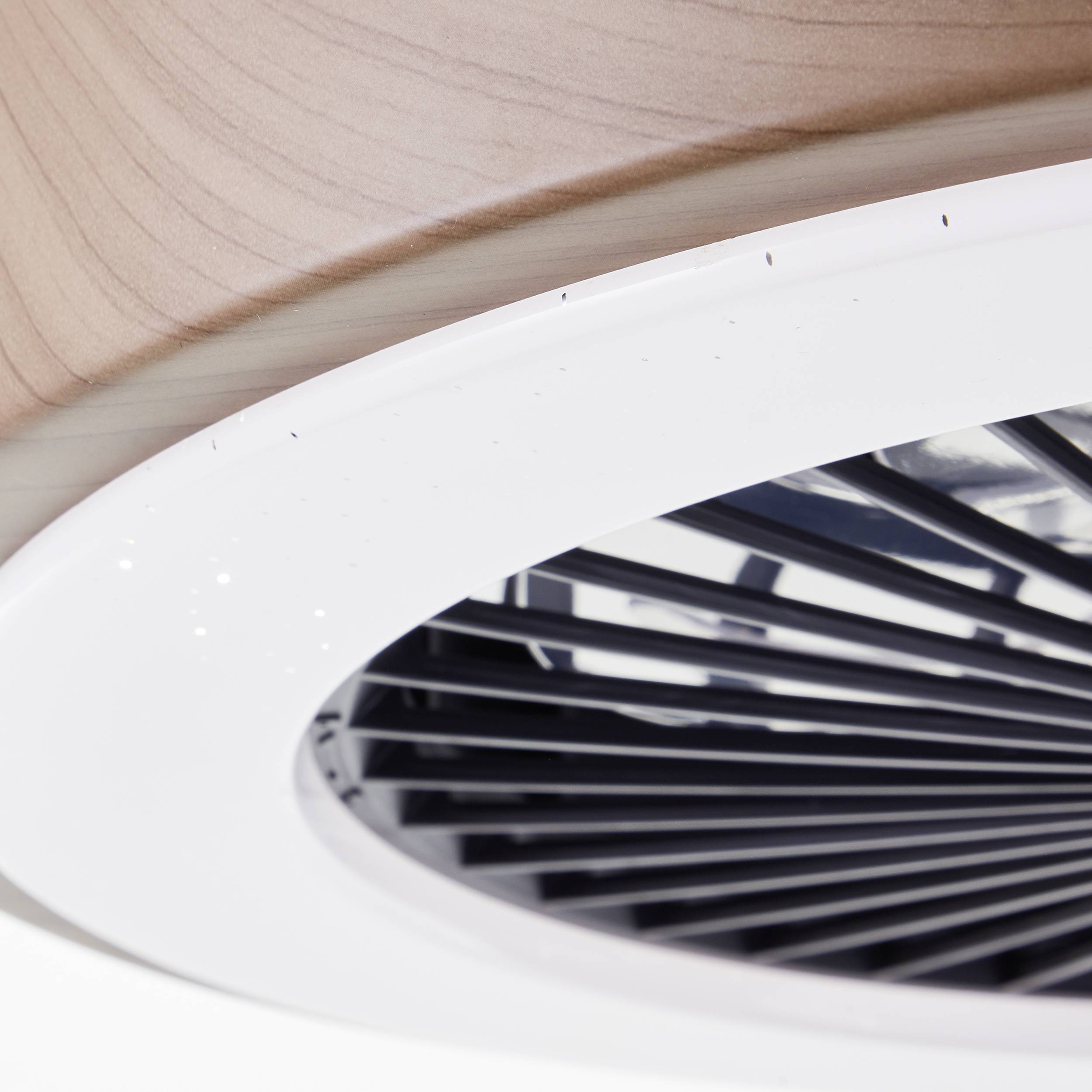 Un ventilateur de plafond moderne avec un motif géométrique sur les pales, dans une pièce bien éclairée.